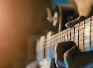 Close-up of a person playing an electric guitar with a blurred background