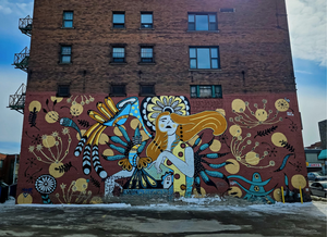 Colorful mural on a brick building with a woman's face and abstract designs.